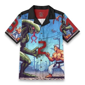 Op de afbeelding: Korte mouwen button-up shirt met een gepixelde afbeelding met een groen, buitenaards wezen en een man in een karate-uniform. Het shirt heeft een blauwe achtergrond met het nummer "2" en een stadsgezicht.