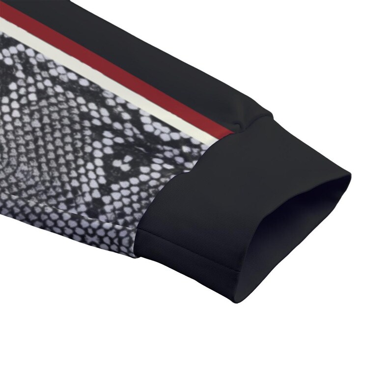 May include: A long sleeve garment featuring a black and white snakeskin pattern on the main body, accented by a vertical stripe in white and red, finished with a solid black cuff at the end of the sleeve to provide a clean and structured look.