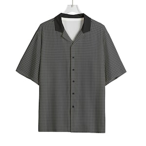 May include: A short-sleeved button-down shirt in a gray grid pattern. The shirt has a black collar and a white inner lining. The shirt is hanging from a white hanger against a white background. The shirt has a relaxed fit.