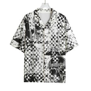 Puede incluir: Camisa de manga corta con un estampado de calaveras y cuadros en blanco y negro. La camisa tiene cuello en V y está colgada de una percha. El diseño incorpora imágenes de calaveras y un motivo a cuadros.