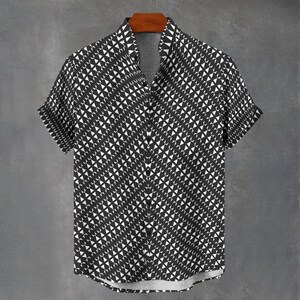 May include: Short-sleeved button-down shirt with a black and white geometric pattern. The shirt is hanging on a wooden hanger against a gray background. The pattern consists of repeating white triangles on a black background.