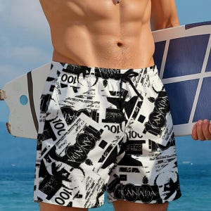 May include: Swim shorts in white and black, featuring a repeating pattern of Canadian currency and text. They have a drawstring waist. The background shows a blue sea.