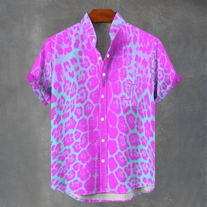May include: A short-sleeved button-down shirt with a vibrant pink and turquoise animal print. The shirt has a mandarin collar and a pocket with an embroidered initial. The shirt is hanging on a wooden hanger.