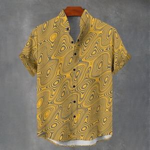 May include: Yellow short-sleeved shirt with a grey, abstract, concentric circle pattern. The shirt has a single chest pocket and black buttons. The shirt is hanging on a wooden hanger against a grey background.