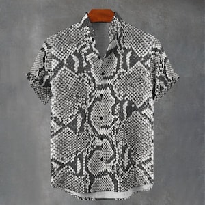 May include: A short-sleeved button-down shirt featuring a monochromatic snakeskin pattern in shades of grey, black, and white. The garment has a standard collar, a central vertical placket with dark buttons, and a straight hemline design.