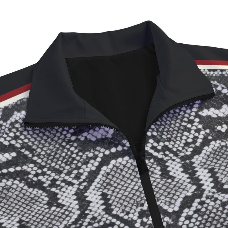 May include: A zip-up jacket featuring a black and white snakeskin pattern across the body. The garment has a solid black collar and a vertical zipper closure. A thin horizontal stripe in red, white, and black accents the shoulder area of the jacket.
