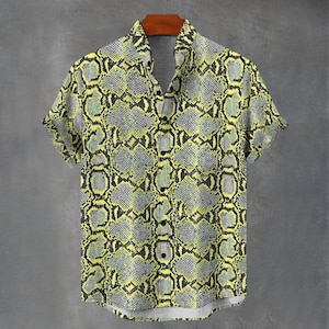 May include: A short-sleeved button-down shirt featuring a vibrant yellow and grey snakeskin pattern. The garment has a standard collar, a front button placket with black buttons, and a straight hemline, showcasing a repeating reptilian scale print.