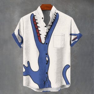 May include: White button-up shirt with a blue cartoon alligator design. The alligator's mouth is open, revealing red teeth. The shirt has short sleeves with blue cuffs and a chest pocket.
