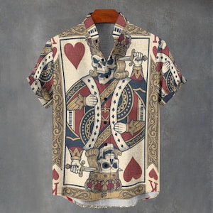 May include: Short-sleeved button-down shirt featuring a playing card design with a skull king holding a knife. The shirt has a beige background with red, blue, and gold accents. The design includes hearts and crowns, creating a unique and eye-catching look.