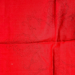 May include: Red fabric with a black paisley pattern. The fabric is folded in half, creating a crease down the center.