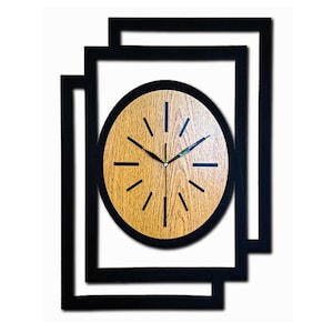 May include: A wall clock featuring a circular face with a light brown wood grain finish, black hour markers, and black hands. The clock is framed by two overlapping black rectangular borders that create a layered, geometric visual effect.