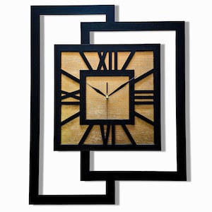 Peut inclure: Une horloge murale carrée avec un cadran doré et des chiffres romains noirs. L'horloge est encadrée dans un cadre carré noir, lui-même inséré dans un cadre noir géométrique plus grand. Les aiguilles de l'horloge sont noires.