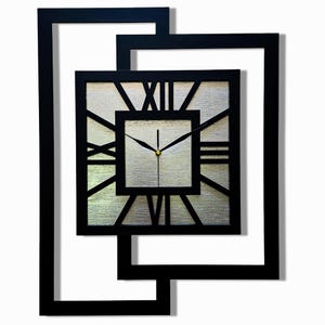 Puede incluir: Reloj de pared cuadrado negro con números romanos y esfera plateada. El reloj está dentro de un marco geométrico negro, creando un diseño moderno y artístico. Las manecillas del reloj son negras con un centro dorado.