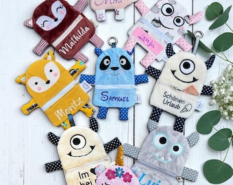 May include: A collection of nine plush monster-shaped zip pouches in various colours and patterns, each featuring embroidered names or phrases like Mira, Mathilda, Lenja, Moritz, Samuel, Schönen Urlaub, Im bei, Luis, and Sophia, with small limbs.
