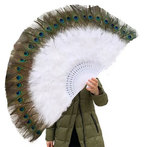 May include: A large white feather fan with peacock feathers along the bottom edge. The fan is held by a person's hand.