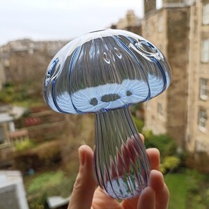 May include: A blue glass mushroom shaped pipe with a textured surface.