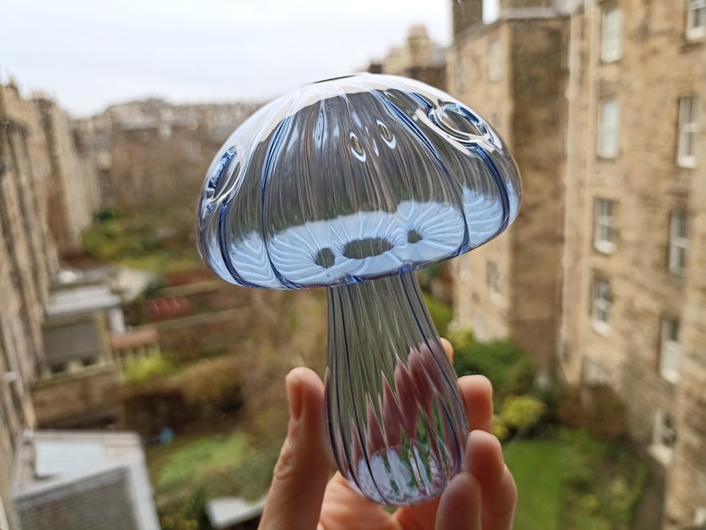 May include: A blue glass mushroom shaped pipe with a textured surface.