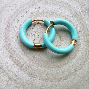 May include: A pair of turquoise hoop earrings with a gold finish. The earrings are simple and elegant.