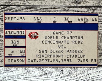 May include: A vintage Cincinnati Reds baseball ticket from a World Champion game against the San Diego Padres at Riverfront Stadium. The ticket is dated September 28, 1991, with seat and gate information.