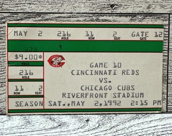 May include: A vintage Cincinnati Reds vs. Chicago Cubs baseball game ticket from Riverfront Stadium, dated May 2, 1992. The ticket shows the game details, seat information, and the Reds logo. The price is $9.00.