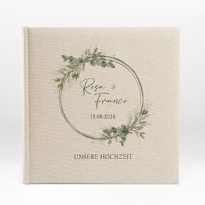 Puede incluir: Un &aacute;lbum de boda de lino beige con una corona de acuarela verde y el texto "Rosa & Franco 15.08.2026 UNSERE HOCHZEIT".
