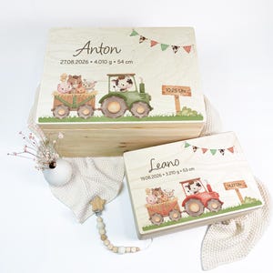 Puede incluir: Dos cajas de madera rectangulares con ilustraciones impresas de un tractor tirando de un remolque con animales de granja. Las cajas están personalizadas con los nombres Anton y Leano, fechas de nacimiento, pesos, longitudes y horas indicadas.