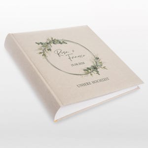 Puede incluir: Un &aacute;lbum de fotos beige con una corona de hojas verdes y el texto "Rosa & Franco 15.08.2026 UNSERE HOCHZEIT"