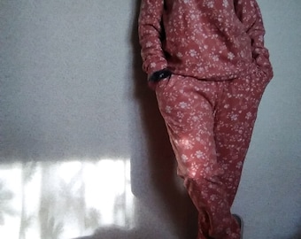 May include: A pink pajama set with a floral print. The top has long sleeves and a crew neck. The pants have a relaxed fit.