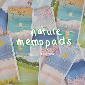 Könnte beinhalten: Ein Set an Notizblöcken mit Naturmotiven und handgemalten Designs. Die Notizblöcke zeigen Szenen von Bergen, Kirschblüten und einem Mond an einem blauen Himmel. Der Text "nature memo pads" ist in Grün auf den Notizblöcken geschrieben. Der Text "@clouds.pmse" ist in Schwarz auf den Notizblöcken geschrieben.