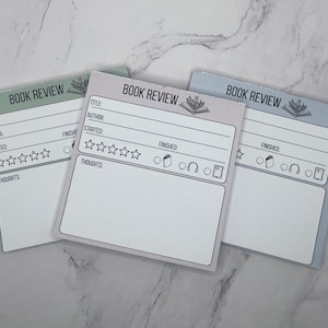 May include: Three rectangular paper note pads for book reviews in sage green, light purple, and light blue. Each pad features the printed text BOOK REVIEW, lines for title, author, start and finish dates, five star icons, and a section for thoughts.