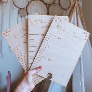 Könnte beinhalten: Wachstumstafeln aus Holz mit graviertem Text und Messmarkierungen. Die Tafeln tragen die Aufschrift "The Chest", "William" und "Watch me Grow". Jede Tafel hat ein Blumendesign und misst bis zu 190 cm.