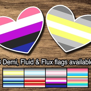 Puede incluir: Dos pegatinas en forma de corazón con diferentes banderas de orgullo. La primera pegatina es rosa, blanca, morada, negra y azul. La segunda pegatina es gris, blanca, amarilla y gris. El texto debajo de las pegatinas dice "8 banderas Demi, Fluido y Flux disponibles".