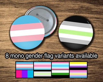 May include: Eight different gender flag variants are shown as button pins. The flags are represented in horizontal stripes of various colors, including pink, blue, white, green, gray, and yellow. The text "8 mono gender flag variants available" is displayed below the buttons.