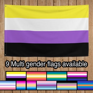 Puede incluir: Una bandera de orgullo de género amarilla, blanca, morada y negra colgada en una pared de paneles de madera. El texto "9 banderas de género múltiple disponibles" está debajo de la bandera. Una fila de nueve banderas de orgullo de género diferentes está debajo del texto.