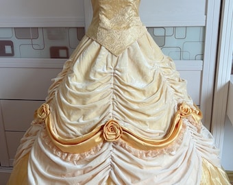 May include: A yellow and white ball gown with a satin bodice and a tulle skirt. The bodice has a floral design with three large roses. The skirt is layered and has a ruffled design.