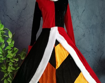 May include: A long, two-tone costume dress with a high collar. The bodice is split vertically, with one side red and the other black. The skirt features a geometric pattern of black, gold, and orange panels, trimmed with white faux fur.