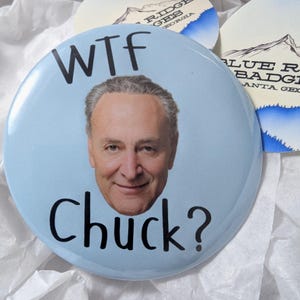 May include: A blue button with the text "WTF Chuck?" and a photo of Chuck Schumer on it.