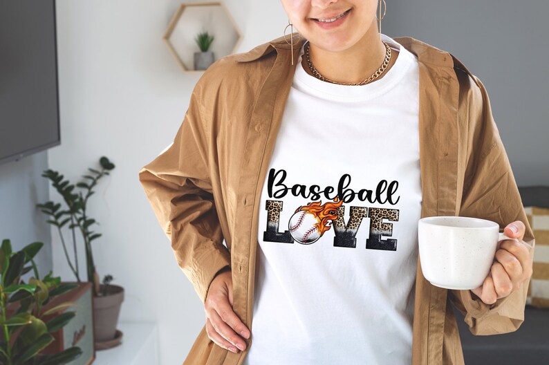 May include: White t-shirt featuring a graphic design of a baseball with flames and the words "Baseball Love" in black and white with a leopard print background.