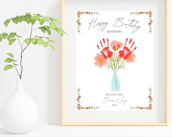 May include: A framed print with a floral design and the text "Happy Birthday Grandma." The artwork features a bouquet of flowers with red handprints and the words "We love you!" and the names "Brian & Lucy" and the year 2024.