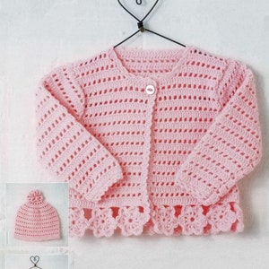 Op de afbeelding: Een roze gehaakte trui met knoopsluiting en een gegolfde zoom. De trui wordt gecombineerd met een bijpassende roze gehaakte muts.