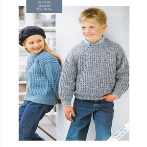 May include: Two children wearing crocheted sweaters. The girl is wearing a blue sweater and a beret. The boy is wearing a gray and white sweater. Both children are wearing blue jeans. The text on the image reads "DK / 8 Ply Crochet 22 to 30 ins"