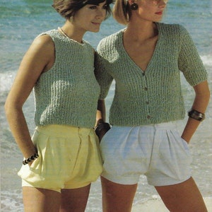 Peut inclure: Deux femmes portant des hauts en tricot et des shorts. La femme de gauche porte un haut vert sans manches et un short jaune. La femme de droite porte un cardigan vert à manches courtes et un short blanc. Les deux femmes sont debout sur une plage de sable.