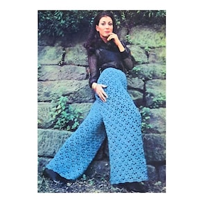 May include: A woman wearing a black top and blue crochet pants. The pants are wide-legged and have a floral pattern.