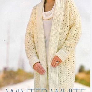 Puede incluir: Un cárdigan de crochet blanco con una abertura larga y abierta en la parte delantera y un cuello ancho. El cárdigan se llama "Winter White Car Coat" y está diseñado por Melissa Leapman.