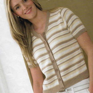 Könnte beinhalten: Ein gestreifter Cardigan mit kurzen Ärmeln und Knopfleiste. Der Cardigan ist in Braun- und Weißtönen gehalten.