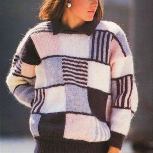 May include: A knitted patchwork sweater in white, pink, grey and dark brown. The sweater has a collared neckline and ribbed cuffs and hem. The person is also wearing a matching dark brown skirt.