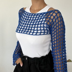 Peut inclure: Un haut en crochet bleu à manches longues et à col large. Le haut est fait d'une maille lâche et ouverte et a un style décontracté et détendu.