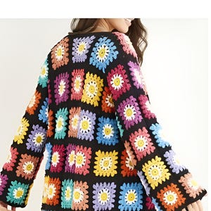 May include: A colorful crochet cardigan with a square pattern featuring a daisy design. The cardigan is made with a variety of colors, including pink, blue, yellow, green, and orange.