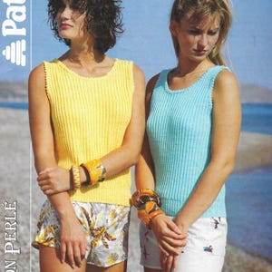 May include: Two women wearing sleeveless knit tops. The woman on the left is wearing a yellow top and the woman on the right is wearing a light blue top. Both women are wearing white shorts.
