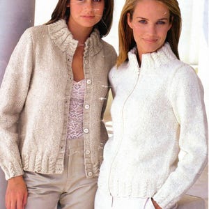 May include: Two women wearing knitted cardigans. The cardigan on the left is a button-up cardigan with a ribbed collar. The cardigan on the right is a zip-up cardigan with a ribbed collar. Both cardigans are a light cream colour.